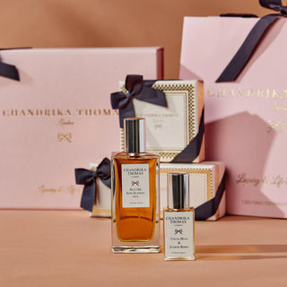 Image of 100ml Allure Rose Blossom Oud Perfume & 15ml Cocoa Bean & Juniper Berry Diffuser with gift boxes and gift bags in the background